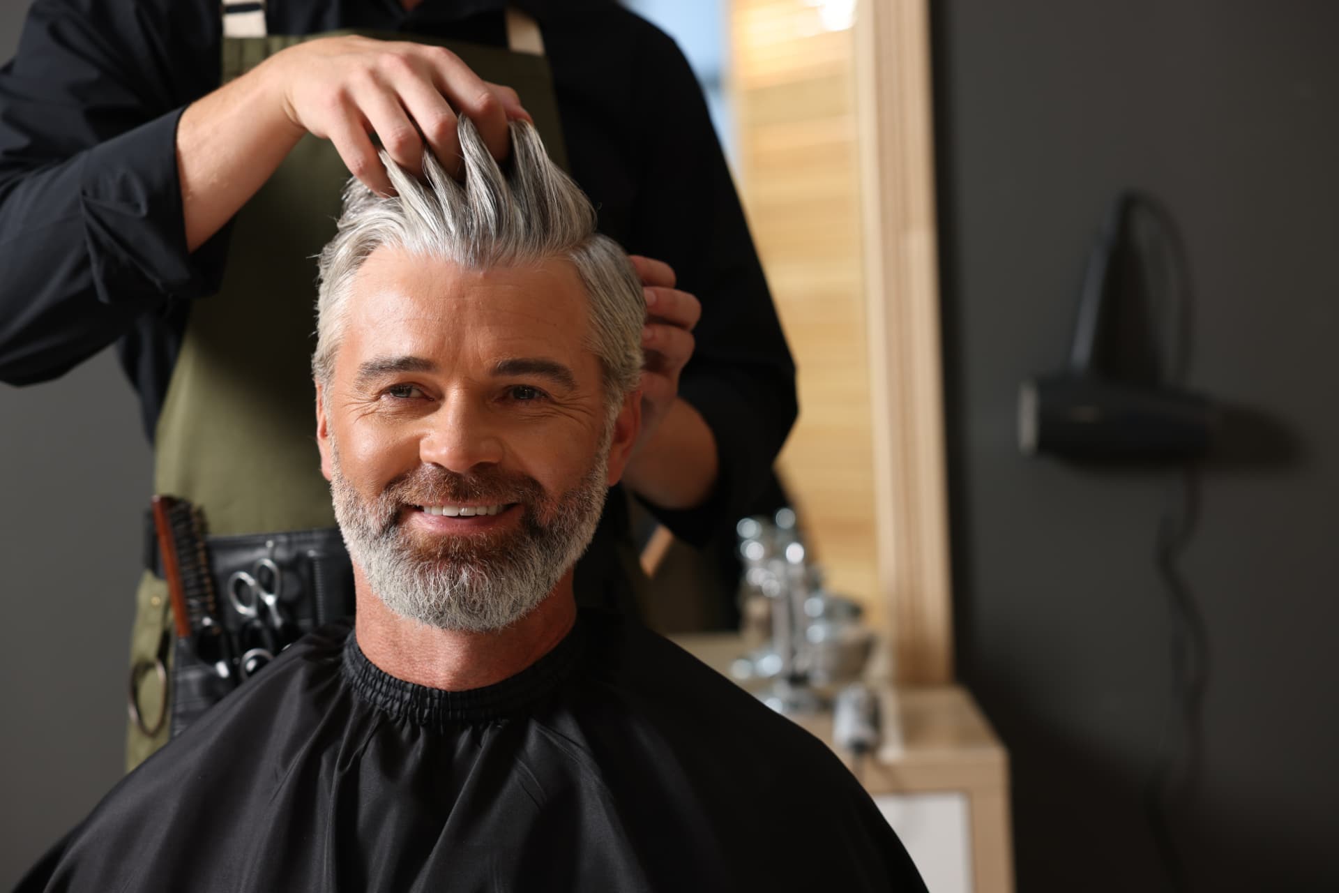 Hair replacement professional styling a client's hair system in a salon